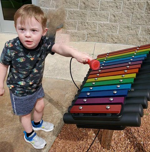 young boy on outdoor musical insturment at the musem